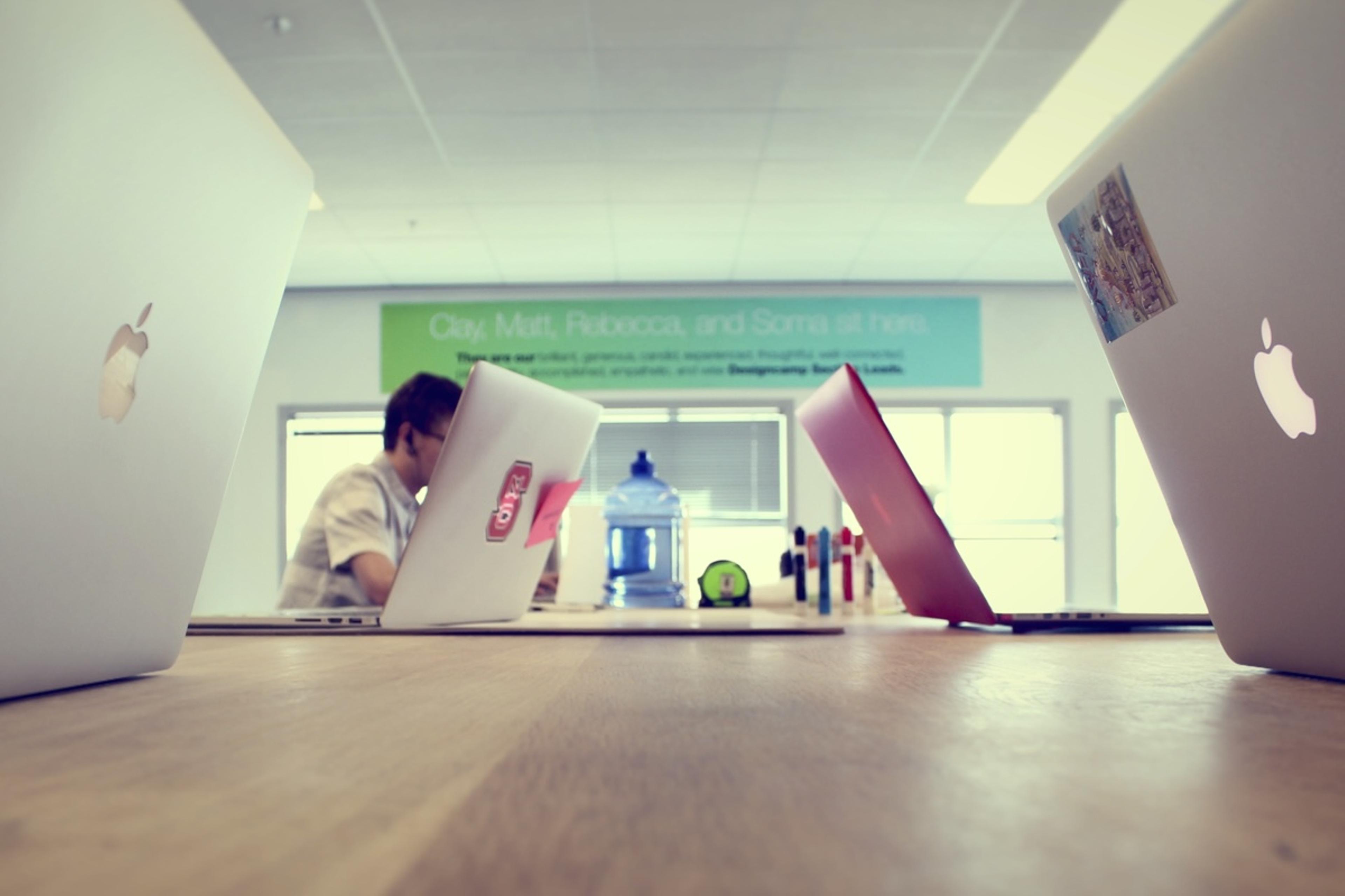 A team of laptops at a block wooden table